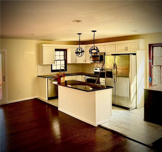 kitchen featuring hanging light fixtures, white cabinetry, appliances with stainless steel finishes, and light hardwood / wood-style flooring