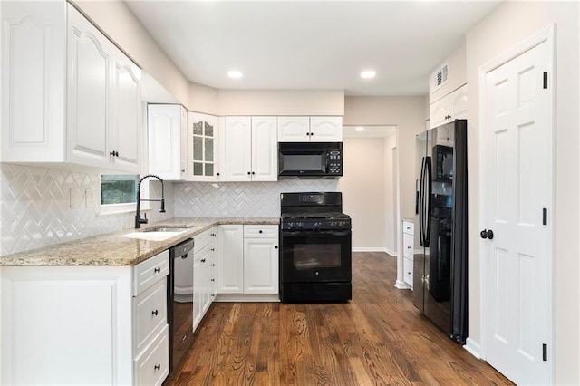 kitchen with white cabinetry, sink, dark hardwood / wood-style flooring, black appliances, and light stone countertops