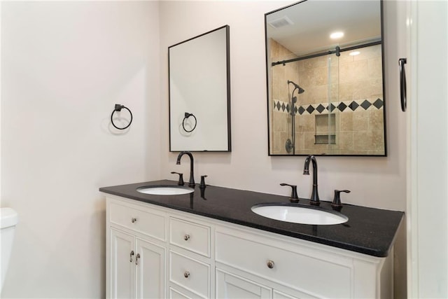 bathroom with vanity, a tile shower, and toilet