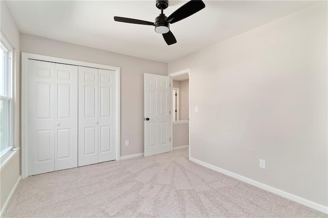 unfurnished bedroom with ceiling fan, light colored carpet, and a closet