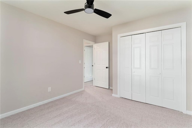 unfurnished bedroom featuring ceiling fan, a closet, and light carpet