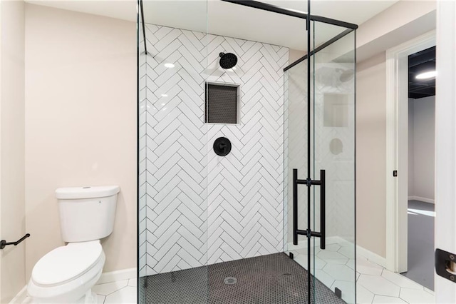 bathroom featuring tile patterned floors, toilet, and tiled shower