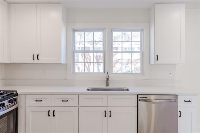 kitchen featuring stainless steel appliances, a healthy amount of sunlight, sink, and white cabinets