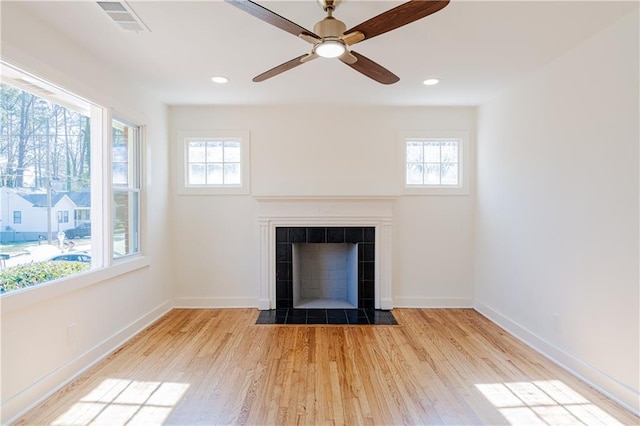 room details with a tiled fireplace, hardwood / wood-style flooring, and ceiling fan