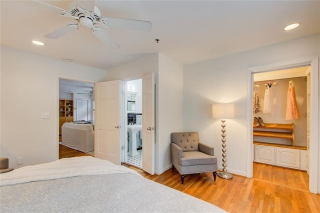 bedroom featuring ceiling fan, light hardwood / wood-style floors, and ensuite bath