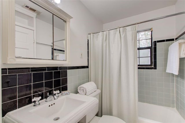 full bathroom featuring shower / tub combo with curtain, toilet, tile walls, and sink