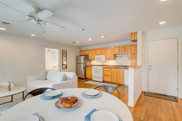 dining area featuring light wood-type flooring, ceiling fan, and sink