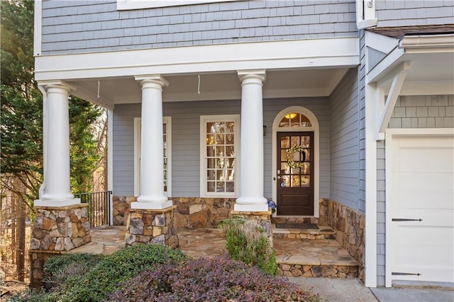 view of exterior entry featuring a garage and covered porch