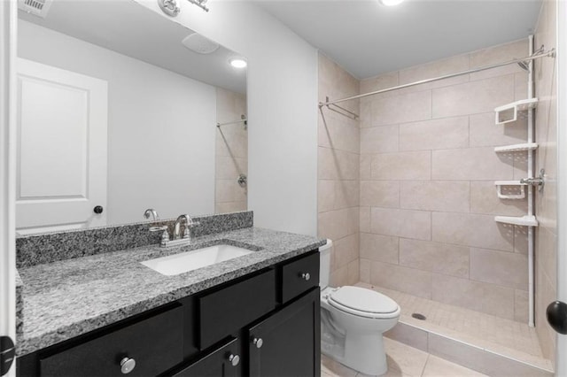 bathroom with vanity, tile patterned flooring, toilet, and a tile shower