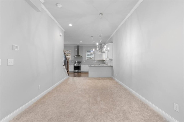 unfurnished living room with ornamental molding, carpet flooring, sink, and a notable chandelier