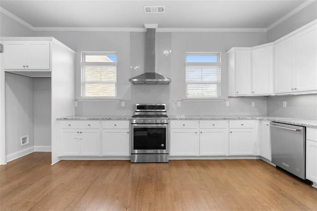 kitchen with stainless steel appliances, white cabinetry, and wall chimney range hood