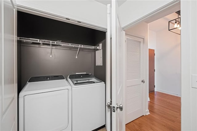 laundry room featuring a notable chandelier, light hardwood / wood-style floors, and washing machine and dryer