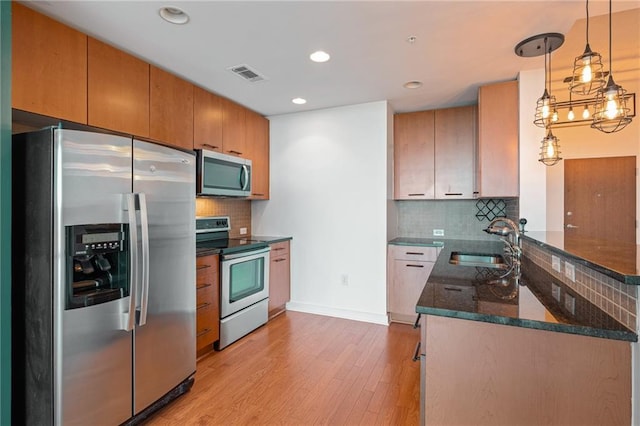 kitchen featuring decorative backsplash, sink, light hardwood / wood-style flooring, and appliances with stainless steel finishes