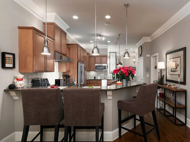 kitchen with a breakfast bar area, decorative light fixtures, ornamental molding, stainless steel appliances, and backsplash