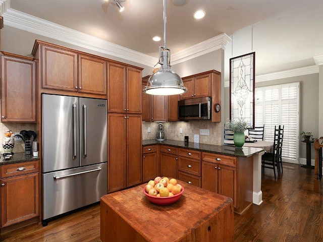 kitchen with appliances with stainless steel finishes, brown cabinets, dark wood-style flooring, ornamental molding, and backsplash