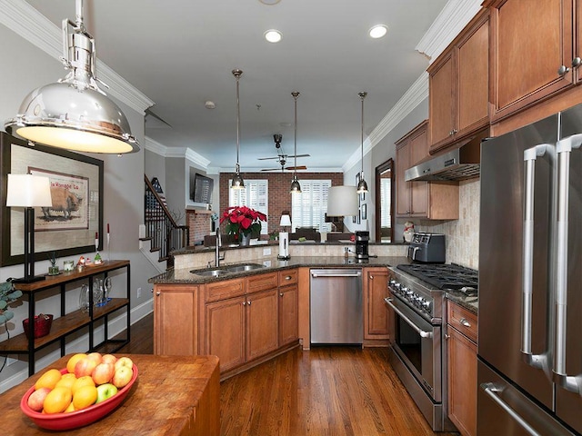 kitchen featuring brown cabinets, high end appliances, a sink, and under cabinet range hood