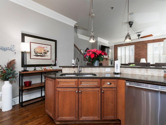 kitchen featuring pendant lighting, crown molding, dark wood finished floors, stainless steel dishwasher, and a sink