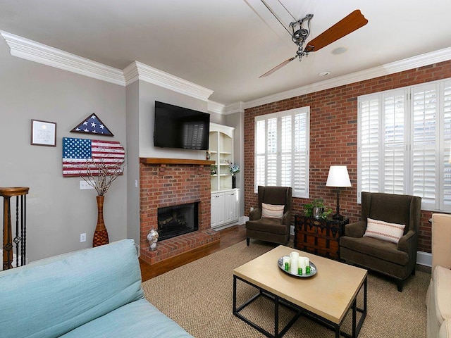 living area featuring ornamental molding, a ceiling fan, a brick fireplace, brick wall, and wood finished floors