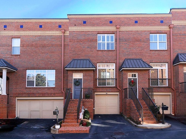 view of property featuring a garage, metal roof, brick siding, and a standing seam roof