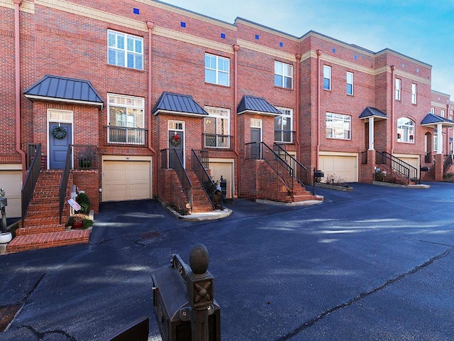 townhome / multi-family property featuring stairs, brick siding, a standing seam roof, and an attached garage