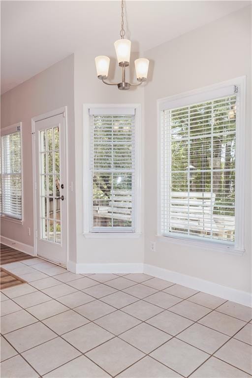 unfurnished dining area with a chandelier, baseboards, and light tile patterned floors