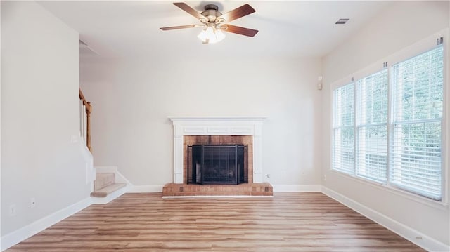 unfurnished living room featuring light wood-style floors, a ceiling fan, a fireplace, baseboards, and stairway