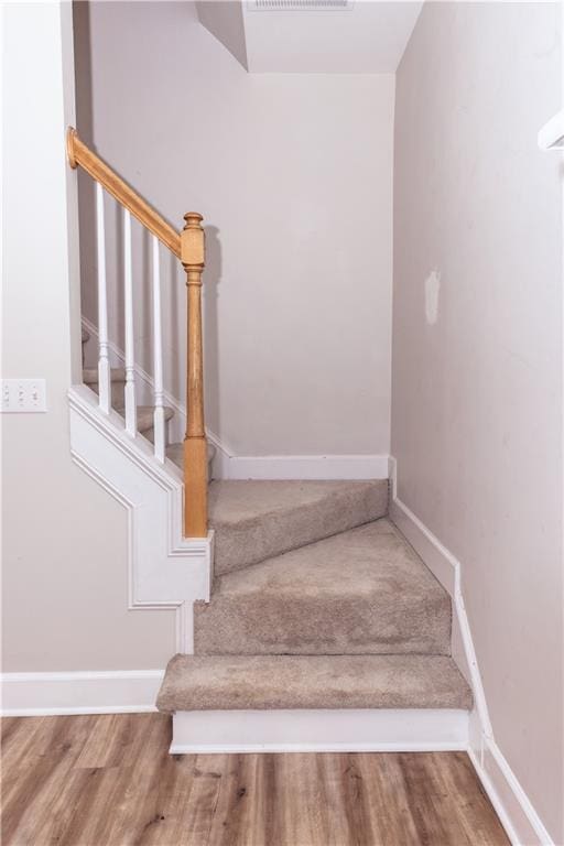 stairway with wood finished floors and baseboards