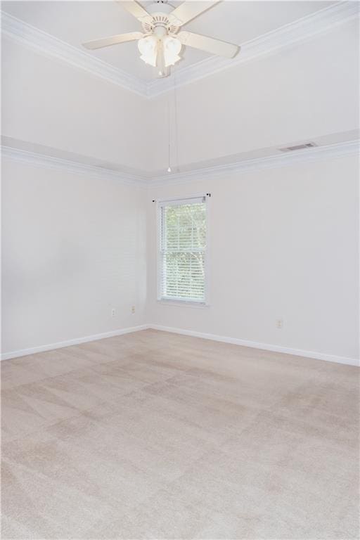 empty room with crown molding, light colored carpet, a ceiling fan, baseboards, and a raised ceiling