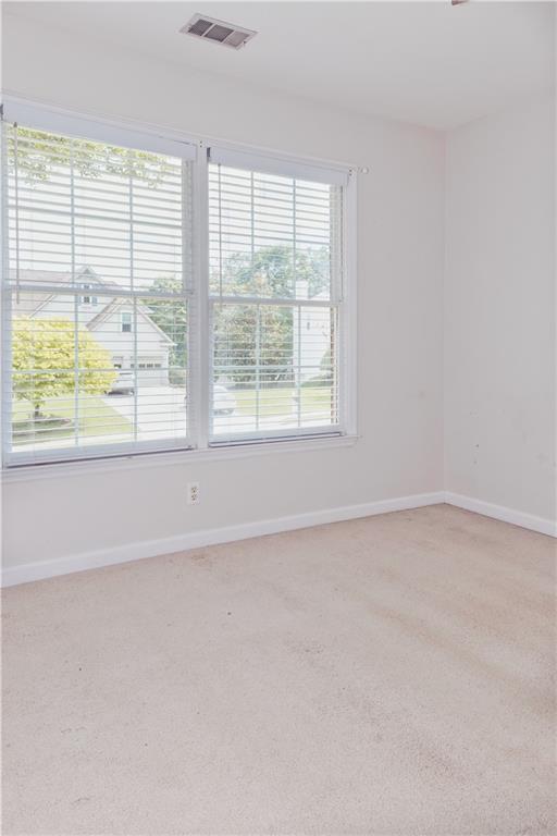 unfurnished room featuring light colored carpet and baseboards