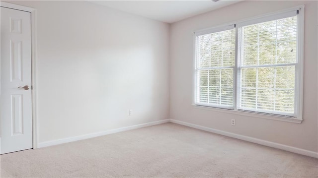 unfurnished room with plenty of natural light, baseboards, and light carpet