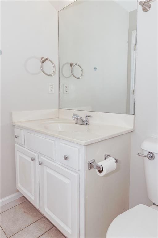 bathroom with toilet, vanity, and tile patterned flooring