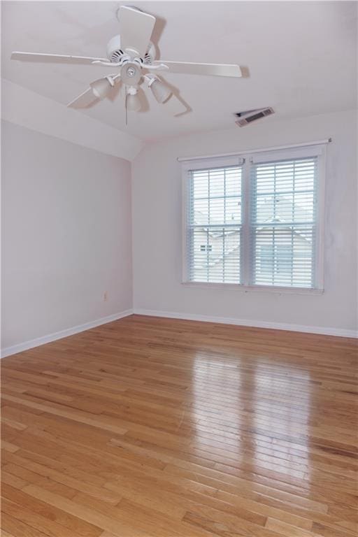 unfurnished room with healthy amount of natural light, light wood-style floors, and vaulted ceiling
