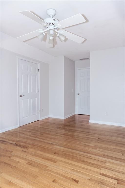 empty room featuring baseboards, light wood finished floors, and ceiling fan