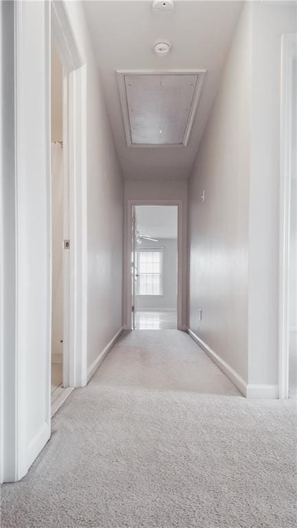 corridor featuring attic access, carpet flooring, and baseboards