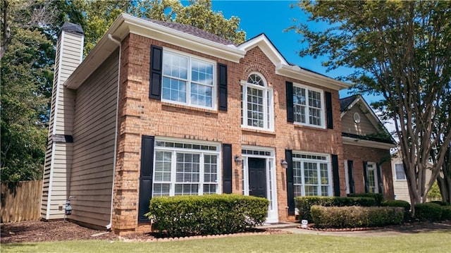 view of front of house featuring brick siding and a chimney