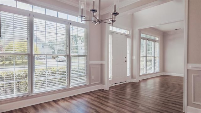 foyer featuring a chandelier, dark wood-style floors, crown molding, and baseboards