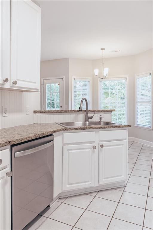 kitchen featuring stainless steel dishwasher, a sink, light tile patterned floors, and a chandelier