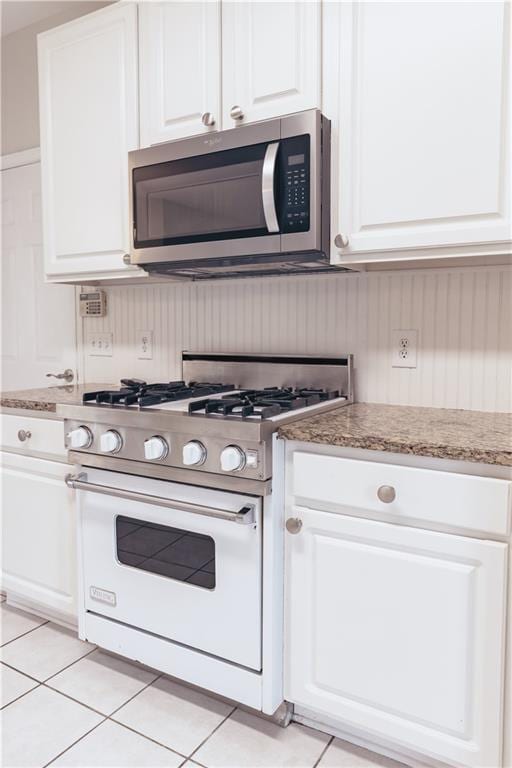 kitchen with stainless steel microwave, high end white range oven, and white cabinetry