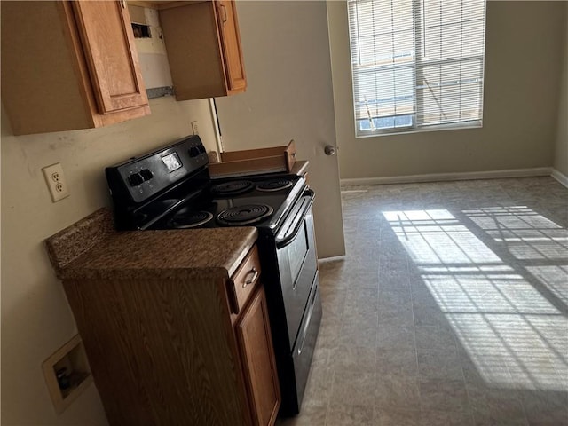 kitchen with dark countertops, black electric range, and brown cabinets