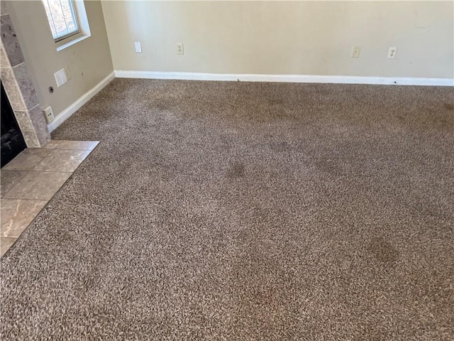 room details featuring a fireplace, carpet flooring, and baseboards