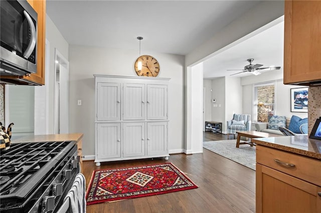 kitchen featuring brown cabinets, open floor plan, stainless steel microwave, and pendant lighting