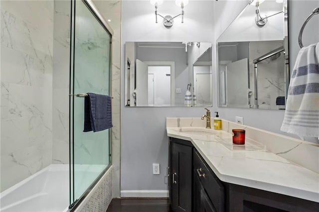 bathroom with combined bath / shower with glass door, vanity, baseboards, and wood finished floors