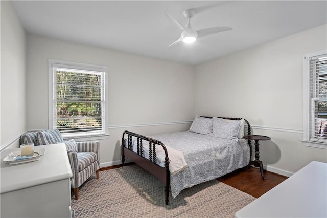 bedroom with ceiling fan, wood finished floors, and baseboards