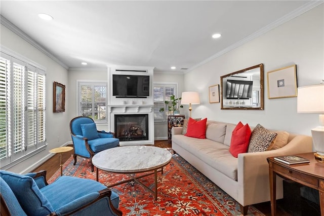 living area featuring recessed lighting, wood finished floors, baseboards, a glass covered fireplace, and crown molding