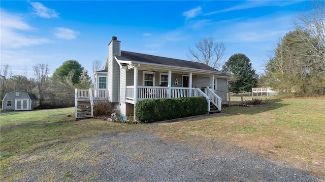 view of front of home featuring a porch, a front yard, a chimney, an outdoor structure, and a storage unit