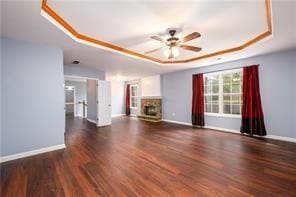 2715 Haynes Club Cir, Grayson, GA 30017 - unfurnished living room featuring a raised ceiling, a fireplace, a ceiling fan, baseboards, and wood finished floors