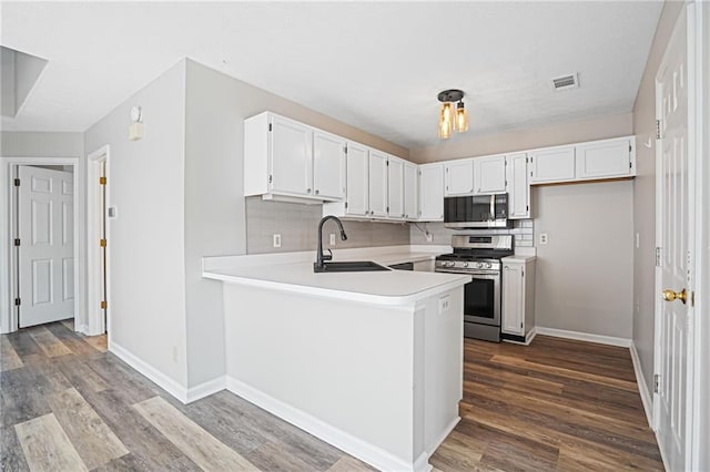 1822 Commonwealth Dr, Woodstock, GA 30188 - kitchen with gas range, light countertops, a peninsula, and dark wood-style floors