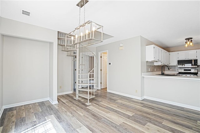 1822 Commonwealth Dr, Woodstock, GA 30188 - kitchen featuring range, light wood finished floors, a chandelier, white cabinetry, and tasteful backsplash