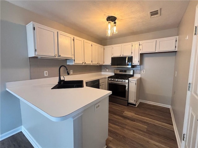 1822 Commonwealth Dr, Woodstock, GA 30188 - kitchen with stainless steel gas range, a sink, a peninsula, dark wood-style flooring, and light countertops