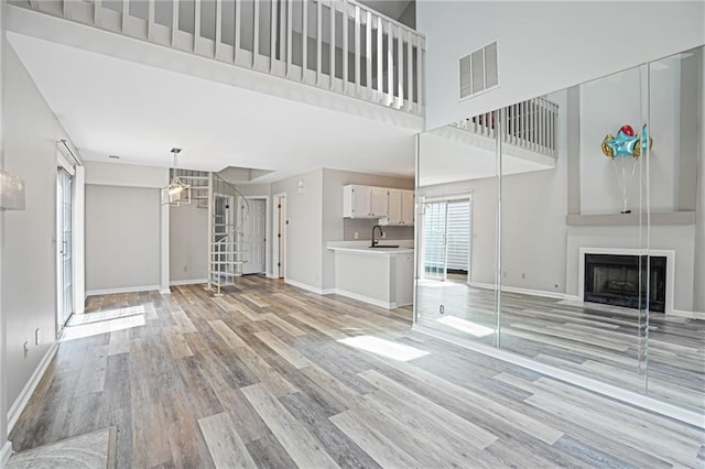 1822 Commonwealth Dr, Woodstock, GA 30188 - unfurnished living room featuring light wood-style floors, a fireplace with flush hearth, and a towering ceiling